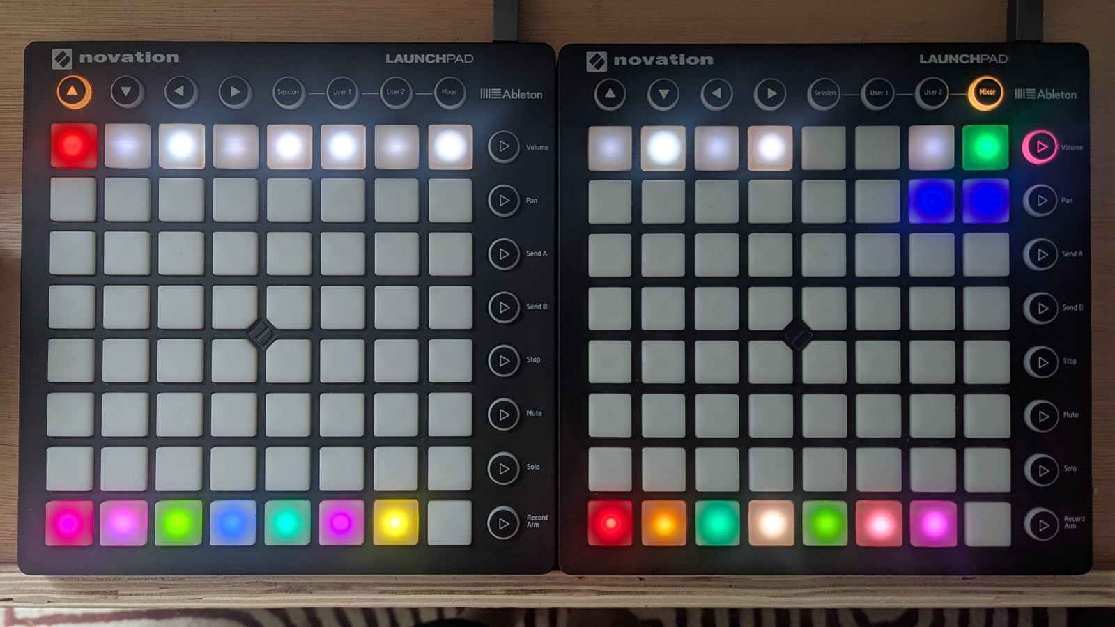 A chord-options grid: the top row is laid out like a piano octave in white and slate with the first pad bright red, the bottom row holds fourteen coloured sequencer pads, the top-right corner is mint green, and the two LPs below the scale selector are blue, photographed on the hardware