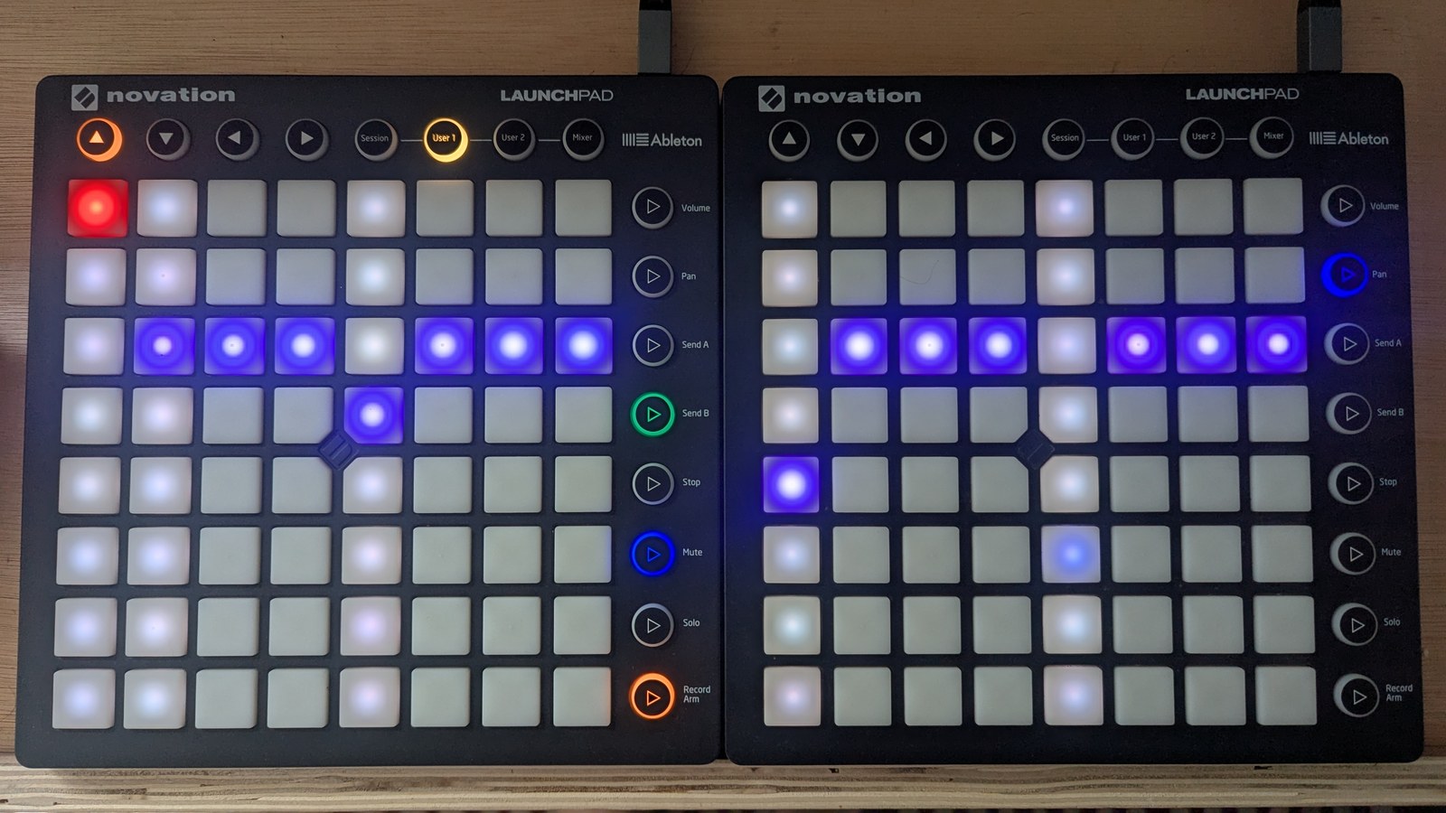 A velocity grid with one lit pad per step, mostly at height 5, red at height 7 on step 1, periwinkle pads stepping down to 4 on step 5 and 3 on step 9, and a deep blue pad at height 2 on step 13, photographed on the hardware