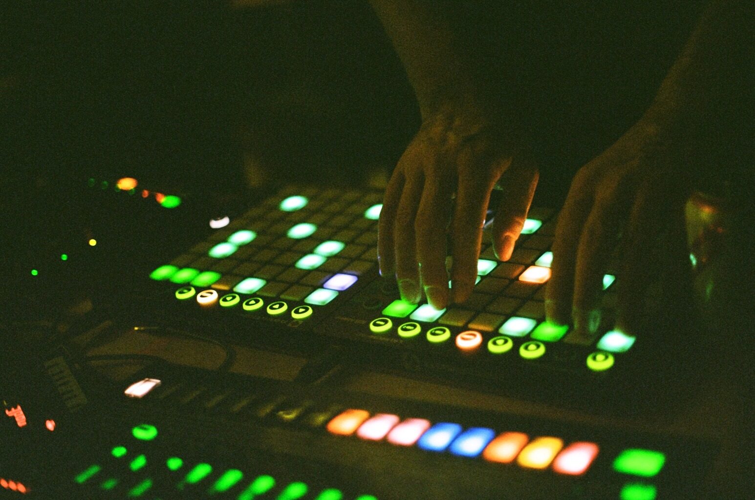 Two hands playing a pair of Launchpads in the dark, with a LaunchControl below